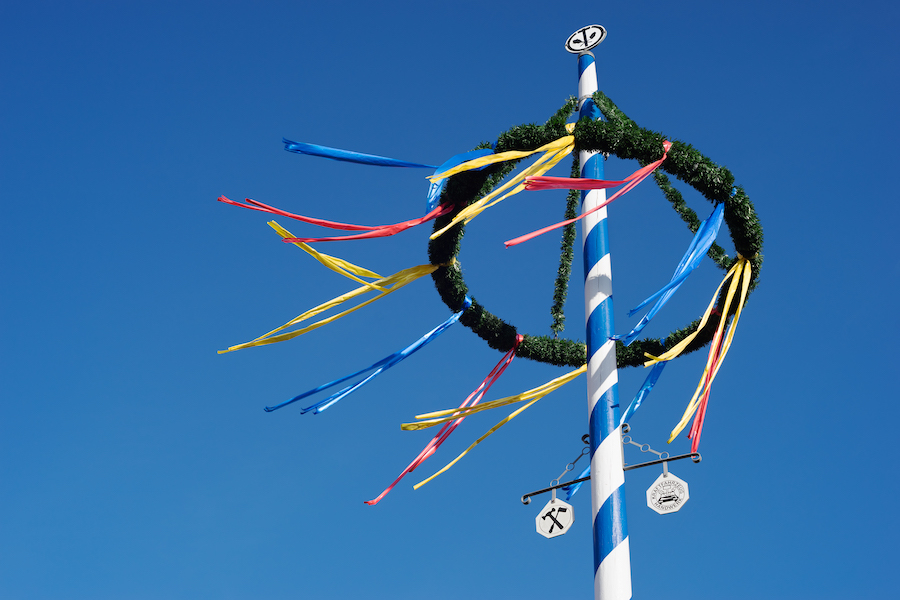 Top of a maypole in Germany, with colorful ribbons hanging off of a wreath