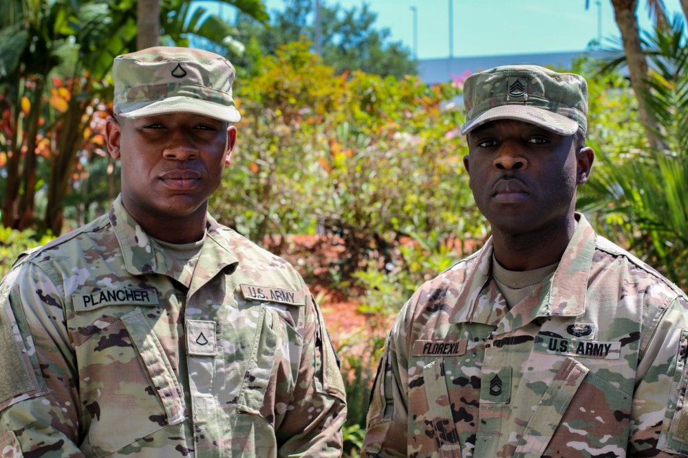 Two men in Army uniforms pose for a photo.