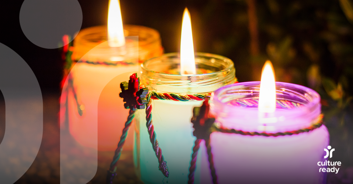 Image of three different colored candles, all lit.