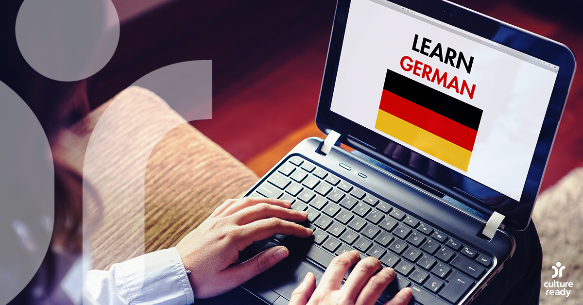 A man is holding a laptop computer that has a German flag on the screen and says "Learn German"