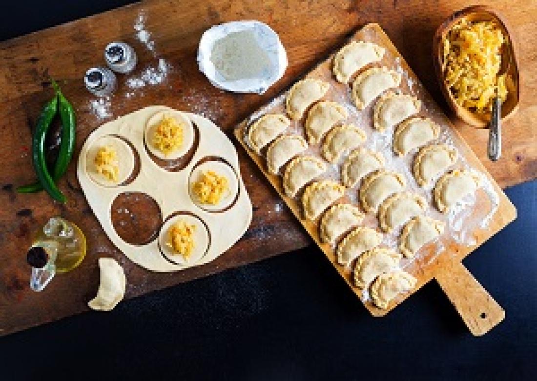 Polish pierogi on a serving board with some waiting to be assembled