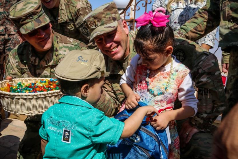 Two servicemen giving school supplies to Jordanian children