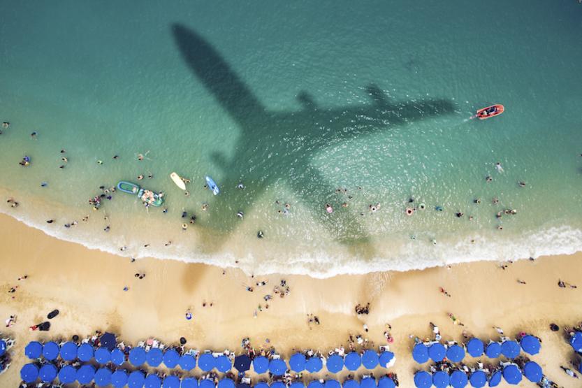 Shadow of an airplane over a crowded beach