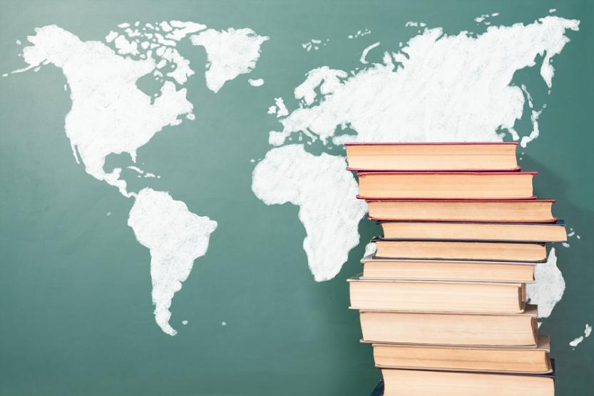 A stack of books in front of a map of the world