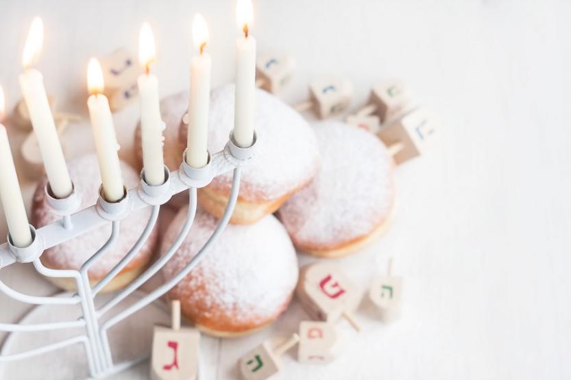 Image of a menorah above a plate of doughnuts.