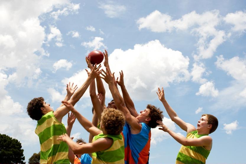 A group of players compete in an Australian rules football match
