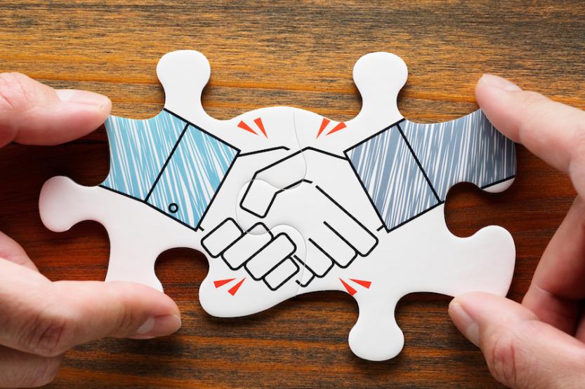 Two puzzle pieces linked together depicting a handshake
