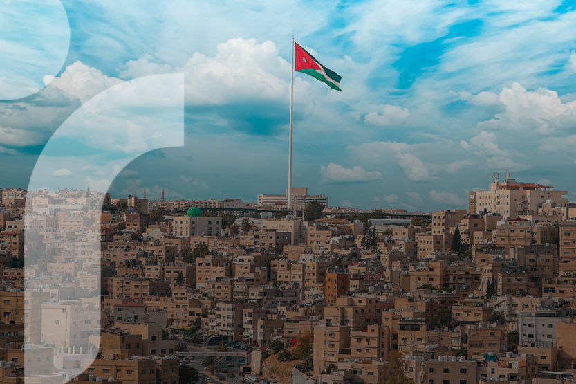 A cityscape of Amman, Jordan with a blue sky and Jordanian flag above the city