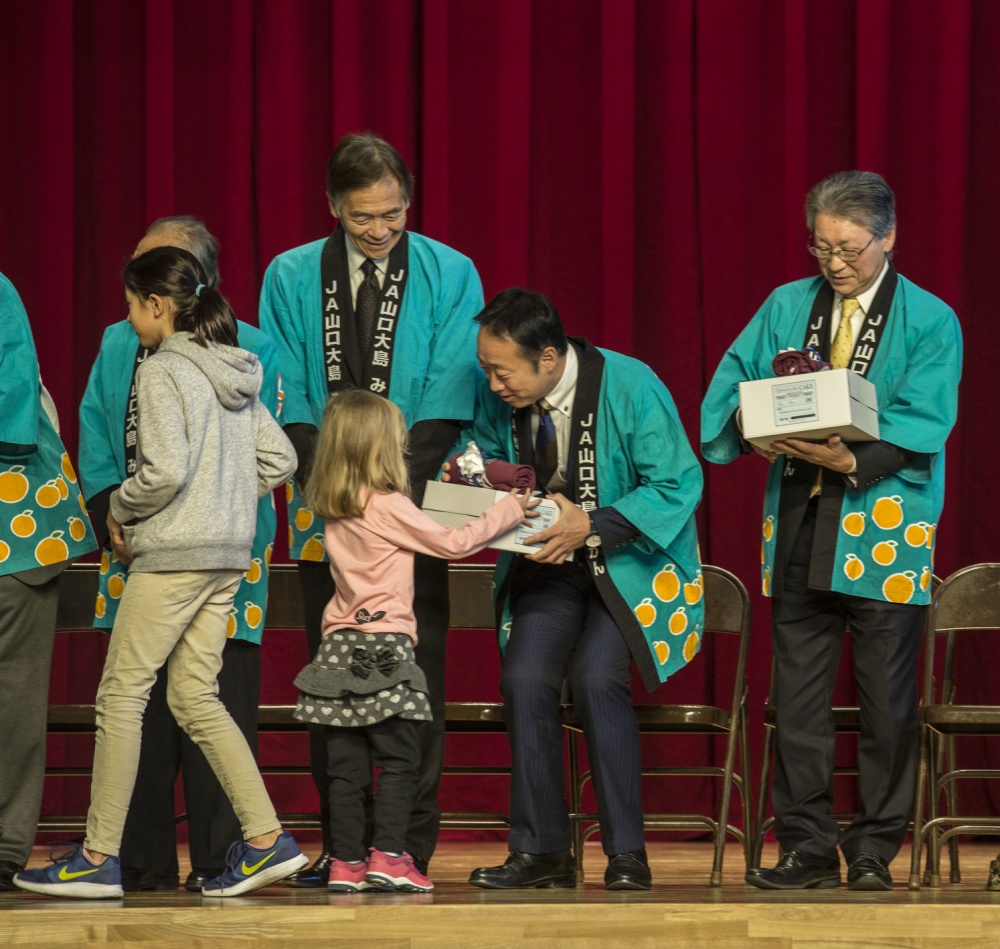 Students from Matthew C. Perry Elementary and Iwakuni Elementary present guests with thank-you gifts during a mikan presentation Marine Corps Air Station Iwakuni, Japan.