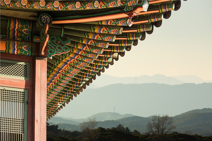 Close-up of a traditional Korean building with mountains in the background