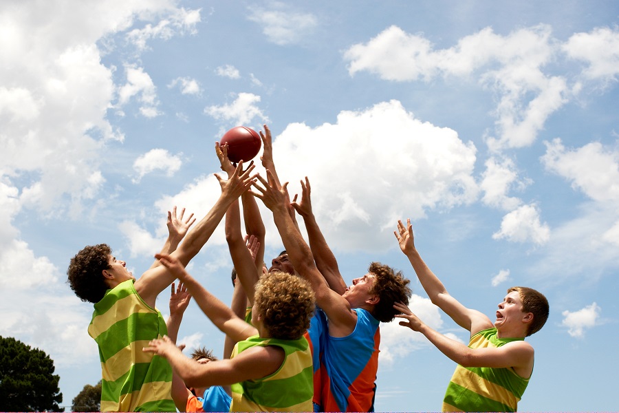 A group of players compete in an Australian rules football match