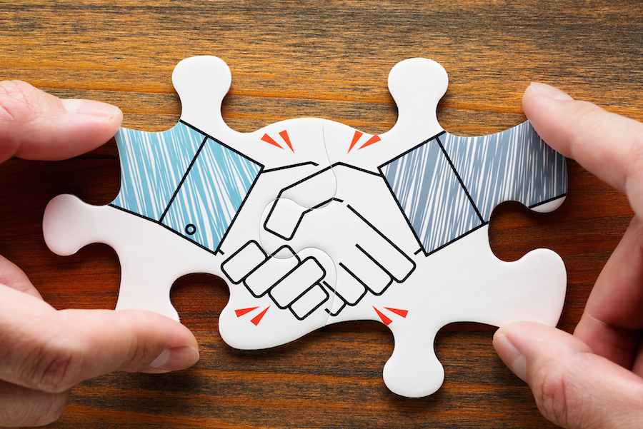 Two puzzle pieces linked together depicting a handshake