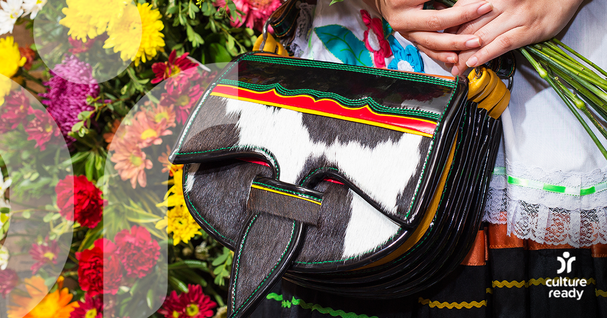 Close-up image of a purse being held by a woman, with flowers in the background