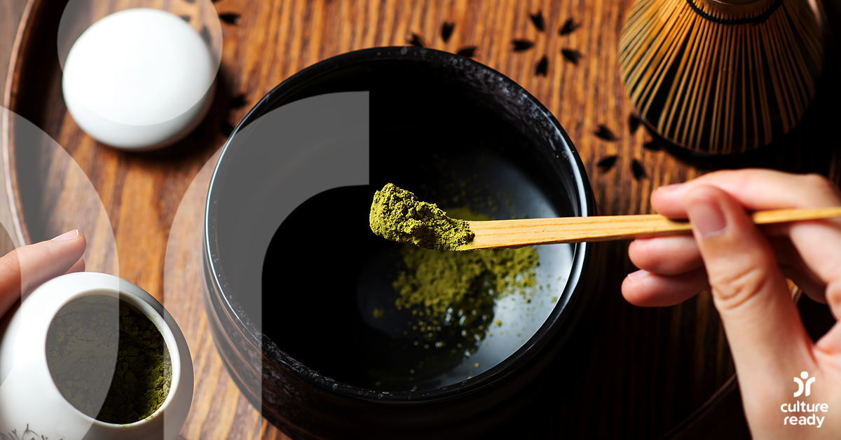 A hand scooping out dry green tea