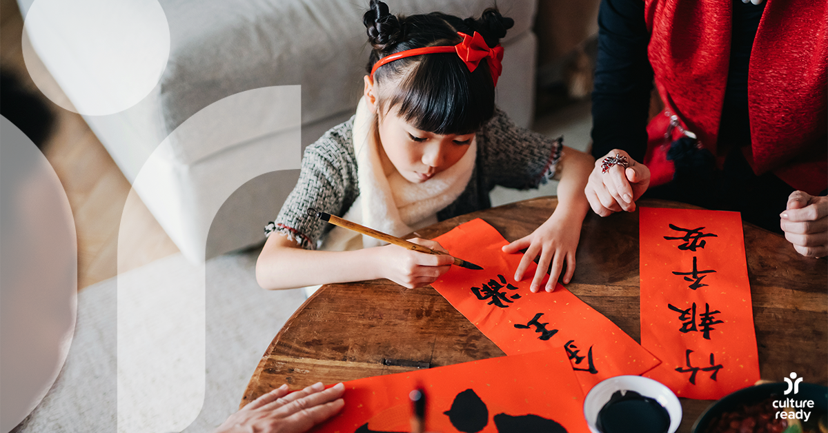 A young girl writing Chinese characters on red paper