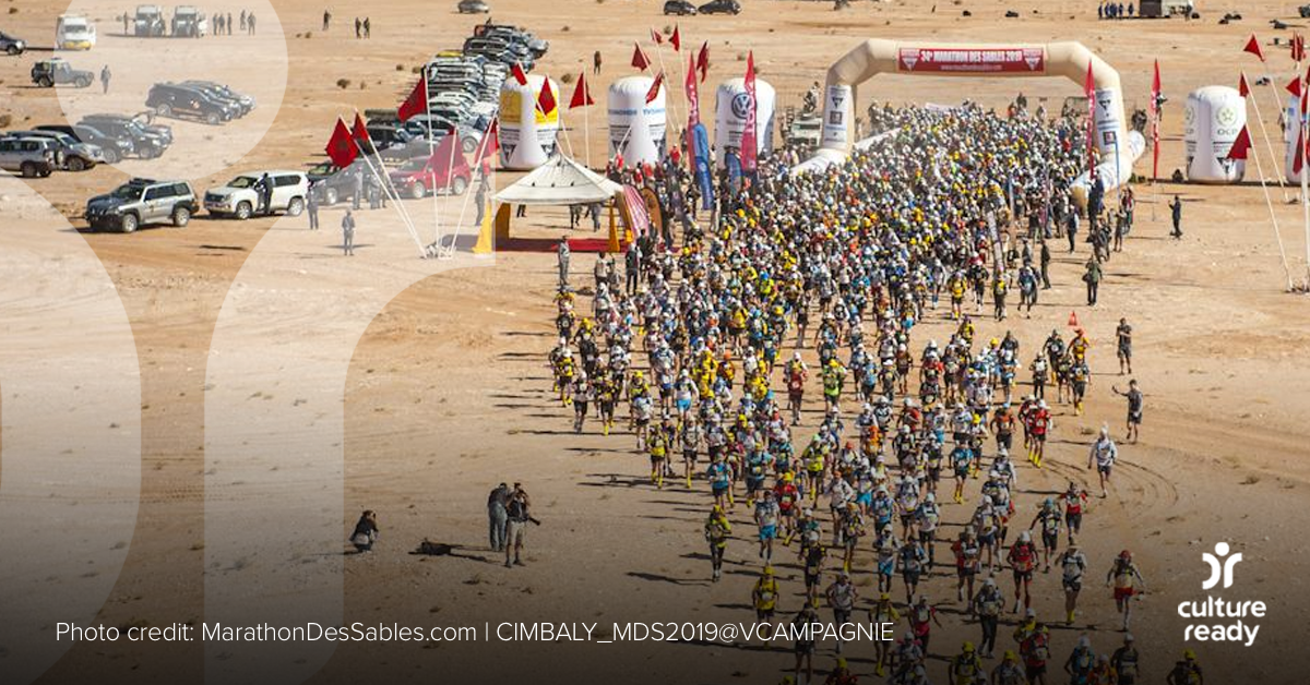 A large group of runners begin a race in a desert landscape