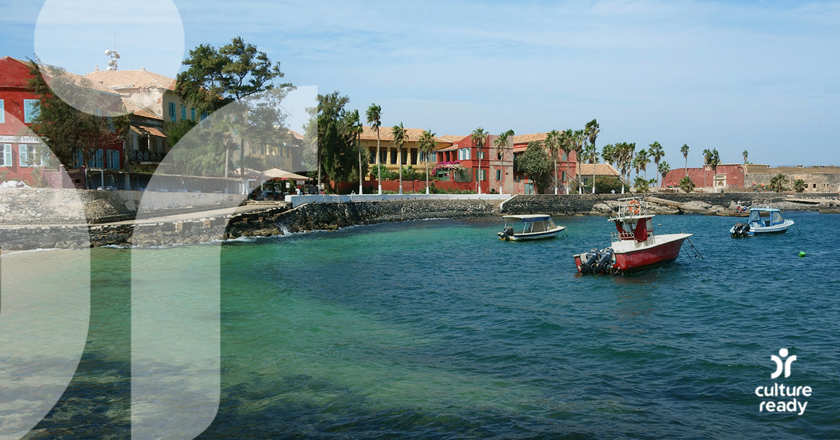 Three fishing boats are in teal water next to a colorful town with palm trees and a blue sky