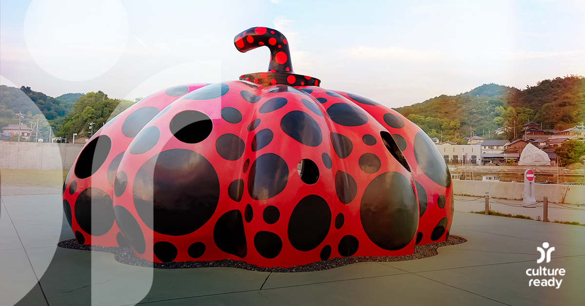 A giant red pumpkin sculpture with black dots by pop artist Yayoi Kusama sits at the end of a pier on the island of Naoshima 