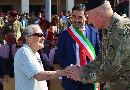 Elderly lady shaking hand of military personnel 