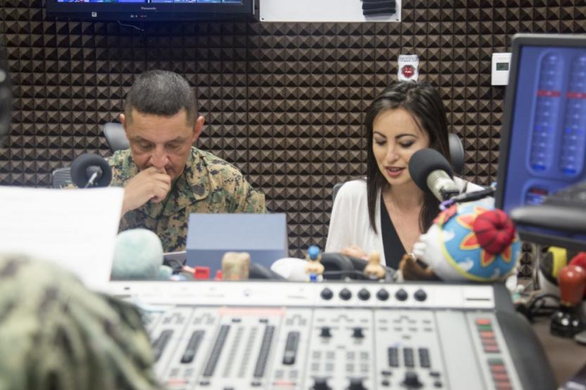 Mari Gregory and Sgt. Maj. Mario Marquez sit in a recording studio as they speak on their radio show.