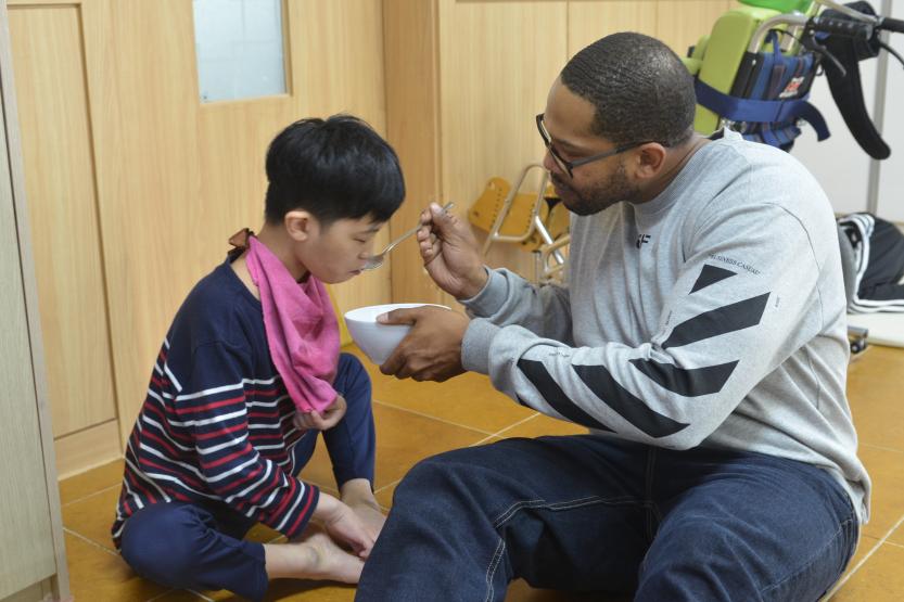 A soldier feeds a special needs resident in an orphanage.