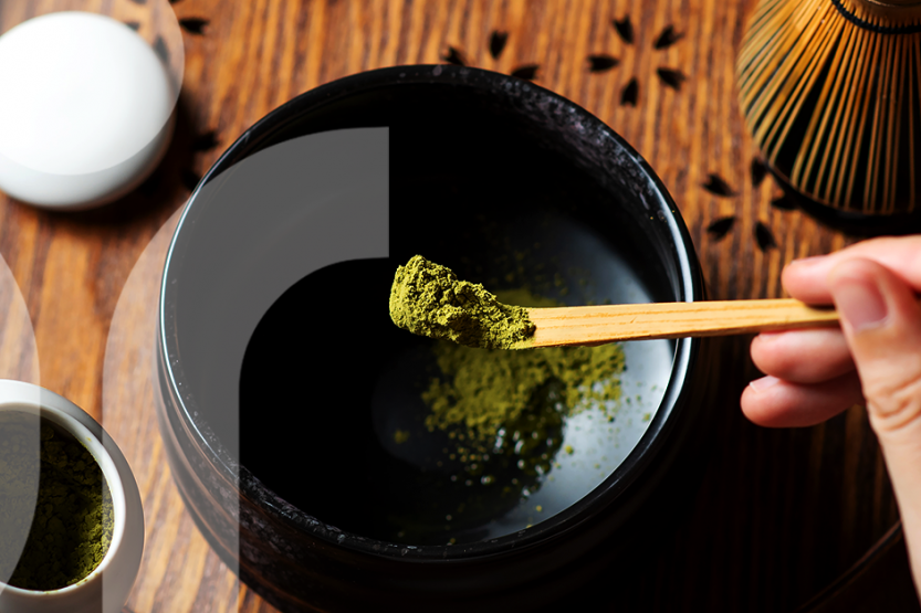 A hand scooping out dry green tea