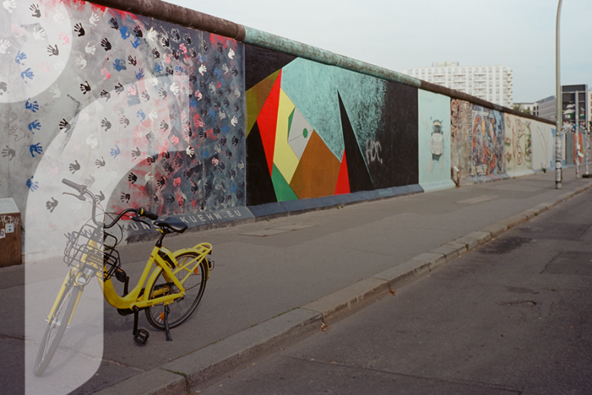 Various murals painted on the Berlin Wall are situated next to a city street