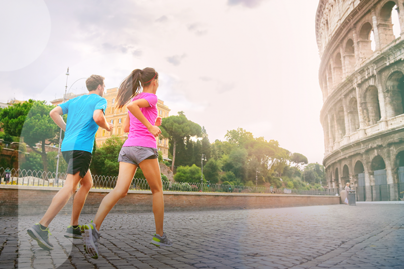 A man and woman in athletic wear run past the Colosseum in Rome
