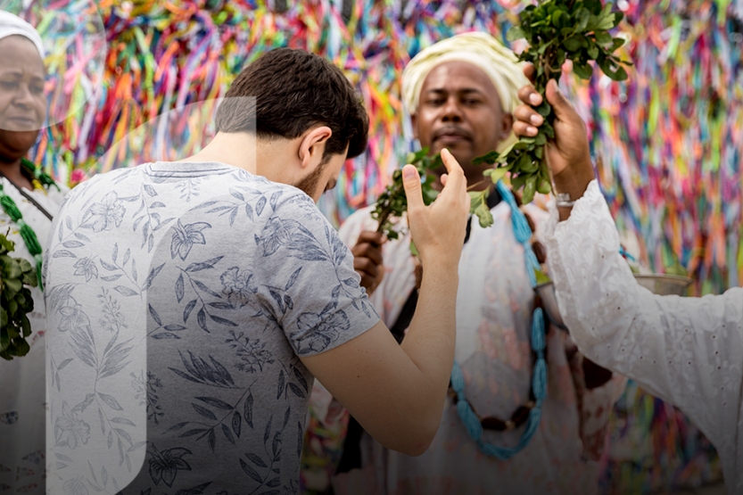 A man in a floral shirt is being blessed by three healers in white, traditional outfits