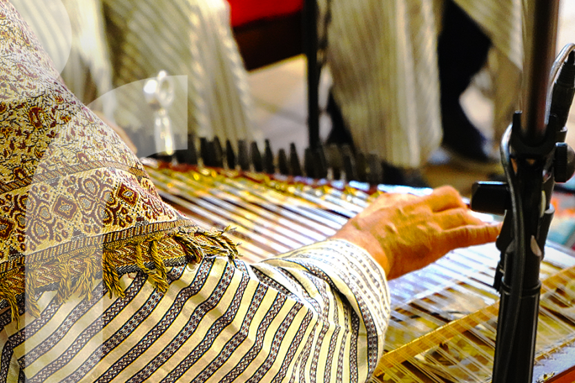 A person in traditional Syrian clothing plays a string instrument