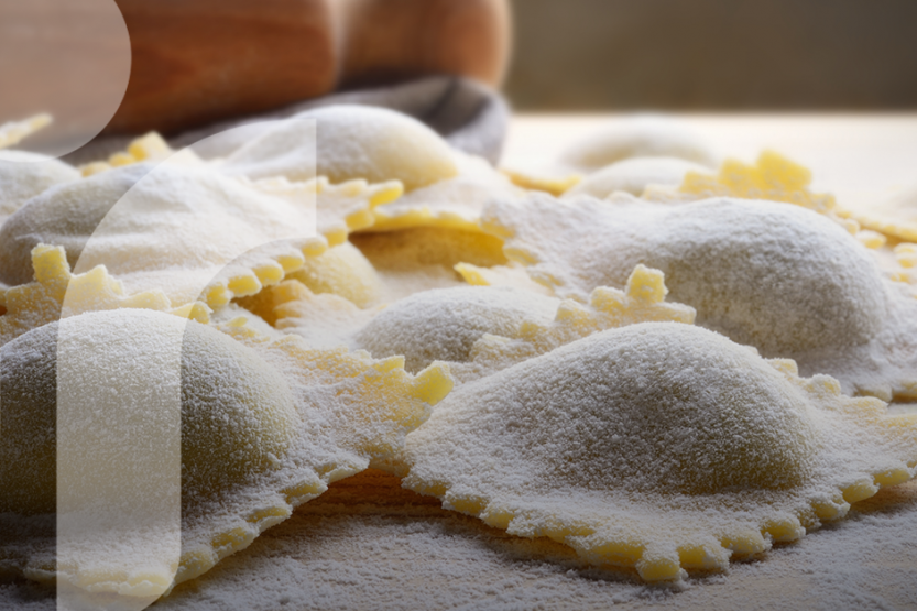 A close up picture of freshly made golden ravioli covered in flour